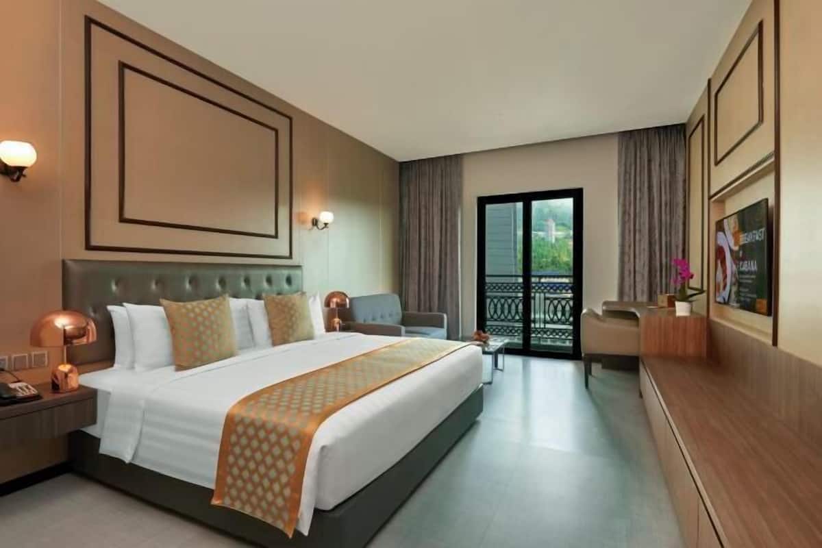 A hotel room with a large bed, a desk, a chair, a TV, and a balcony with a view.