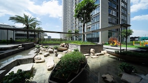 A rooftop garden with stone planters, a playground, and a modern building in the background. - Jaan Apartment 29 Lieu Giai (Hanoi)