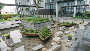 A modern outdoor area with a children's play area, potted plants, and a water feature. - Jaan Apartment 29 Lieu Giai (Hanoi)