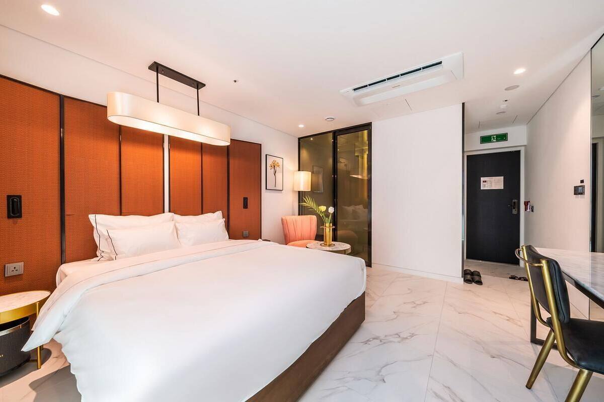 A hotel room with a large bed, a desk, and a chair.