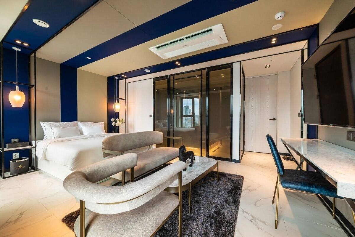 A modern bedroom with a bed, sofa, and a dining area with a table and chairs.