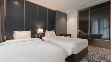 A hotel room with two beds, a desk, a chair, and a large mirror.