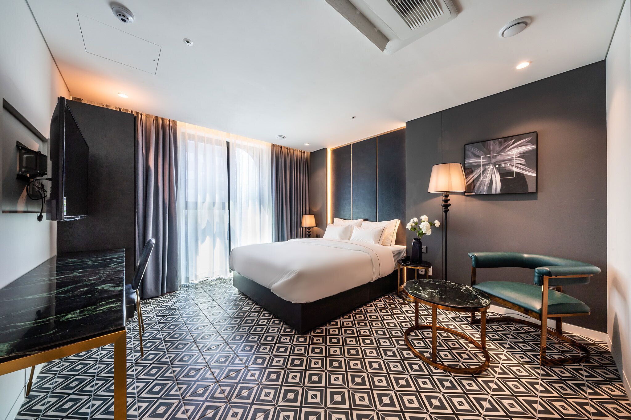 Ein modernes Hotelzimmer mit einem großen Bett, einem Fernseher, einem Schreibtisch und einem Stuhl.
