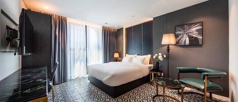 Ein modernes Hotelzimmer mit einem großen Bett, einem Fernseher, einem Schreibtisch und einem Stuhl.