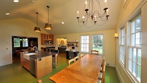 A spacious kitchen with a large island, wooden cabinets, and a chandelier.