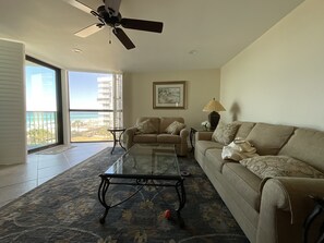 A living room with a glass coffee table, a beige sofa, and a ceiling fan. - Luxury Condo. Amazing Gulf views. Beach-facing balcony. Private Resort Amenities (Destin)