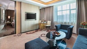 Une chambre d’hôtel moderne dotée d’une grande fenêtre, d’un téléviseur à écran plat, d’une table basse ronde et d’un canapé.