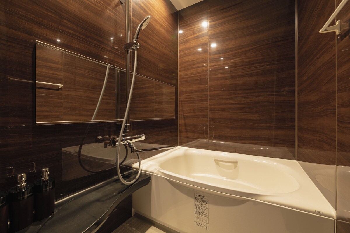 A modern bathroom with a large bathtub, a glass-enclosed shower, and a mirror above the sink.