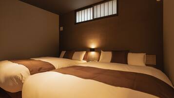 A hotel room with two beds, a window, and a wall-mounted light fixture.