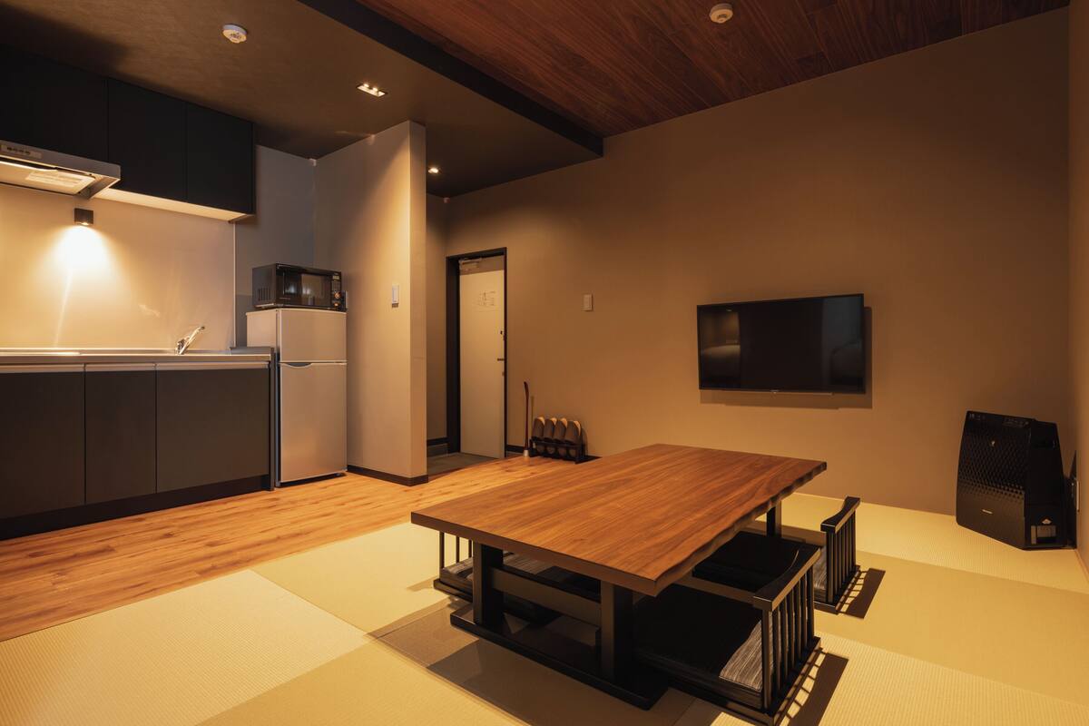 A modern kitchen with a wooden table, a microwave, and a refrigerator.