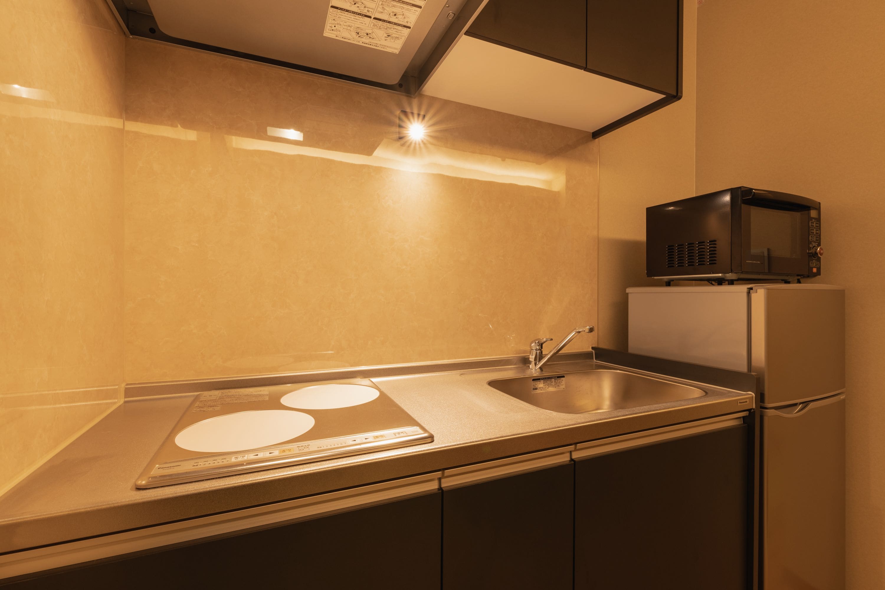 A compact kitchen with a stainless steel sink, a microwave, and a refrigerator.