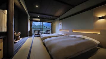 A hotel room with two beds, a view of the mountains, and a small dining area with a table and chairs.