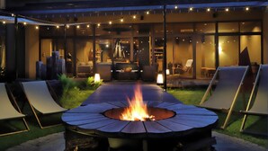 A fire pit surrounded by lounge chairs, a covered patio area, and string lights. - Oyado Morinone - Adults Only (Kaminoyama)
