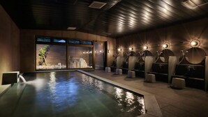 A spa area with a pool, multiple showerheads, and a view of a forest through the windows. - Oyado Morinone - Adults Only (Kaminoyama)