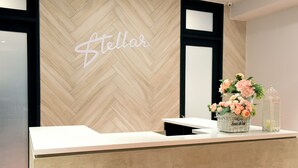 A reception desk with a herringbone wood panel wall, a 'Stellar' sign, and a floral arrangement. - Stellar Potter's Ridge (Laurel)