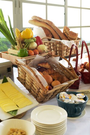 A breakfast buffet with various breads, fruits, and pastries.