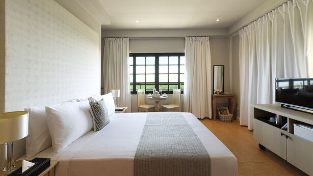 A hotel room with a large bed, a TV, a desk with a chair, and a window with curtains. - Stellar Potter's Ridge (Laurel)