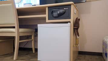 Un espacio de oficina compacto con escritorio, silla y un mini refrigerador blanco con panel de control.