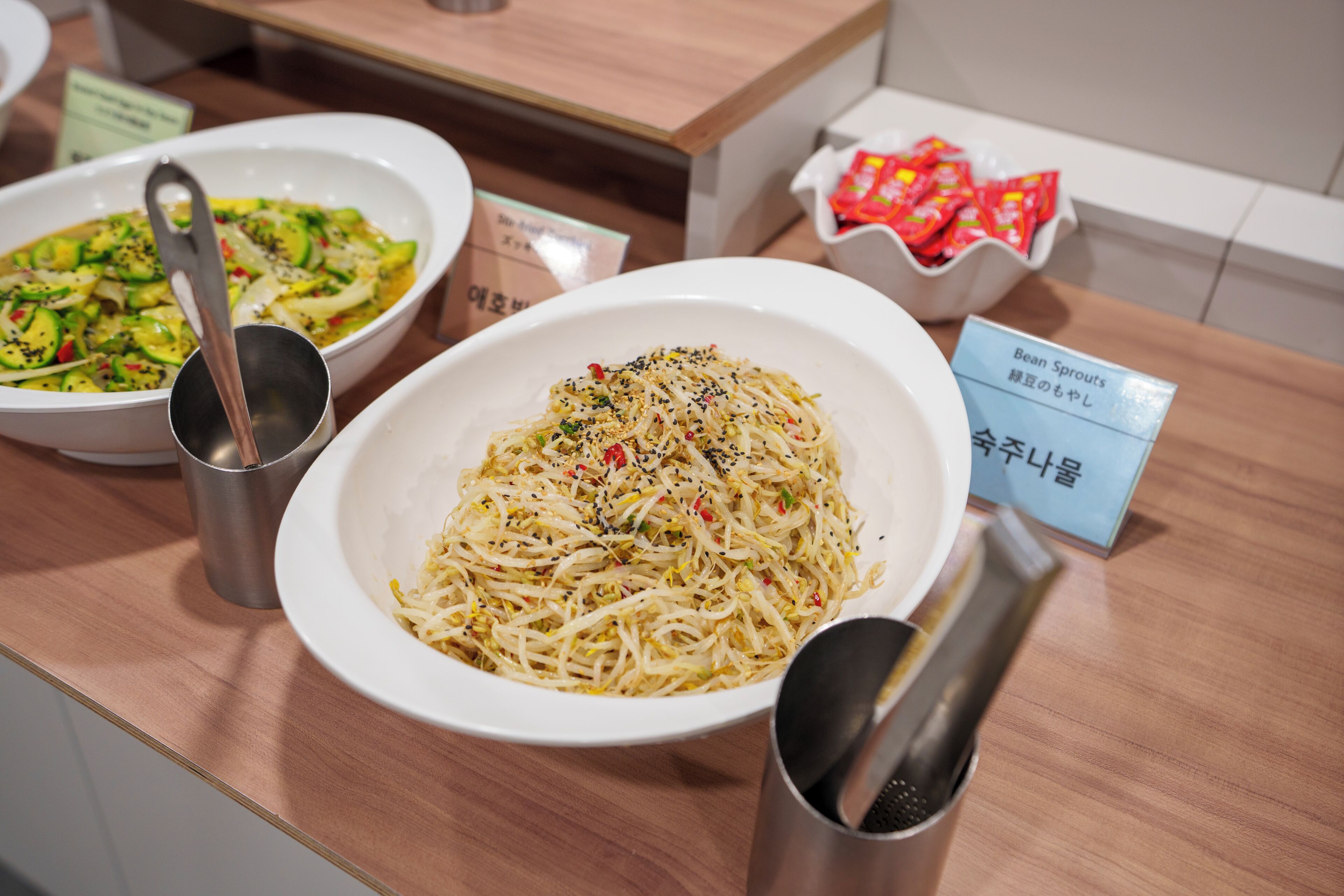 A dining table with two bowls of food, a metal cup, and a sign with foreign text.