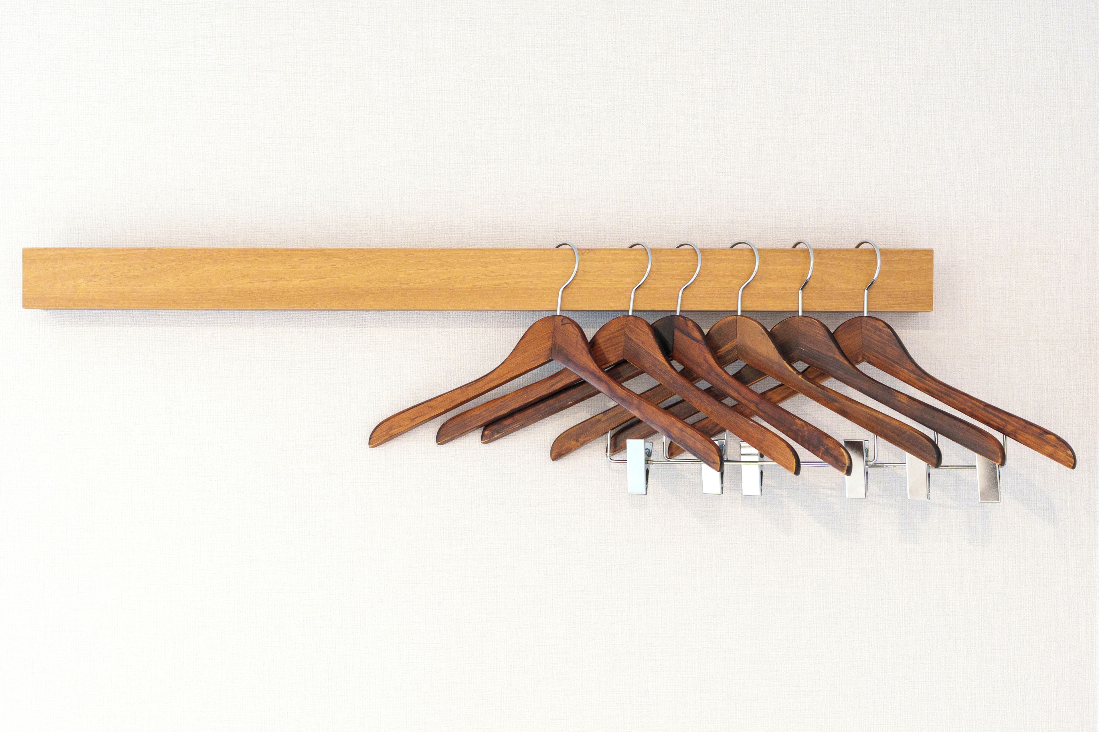 Un porte-manteau en bois, doté de plusieurs patères, est adossé à un mur uni.