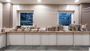 A modern kitchen with white cabinets, stainless steel appliances, and a long countertop with various food items and utensils. - Toyoko Inn Ulsan Samsandong (Ulsan)
