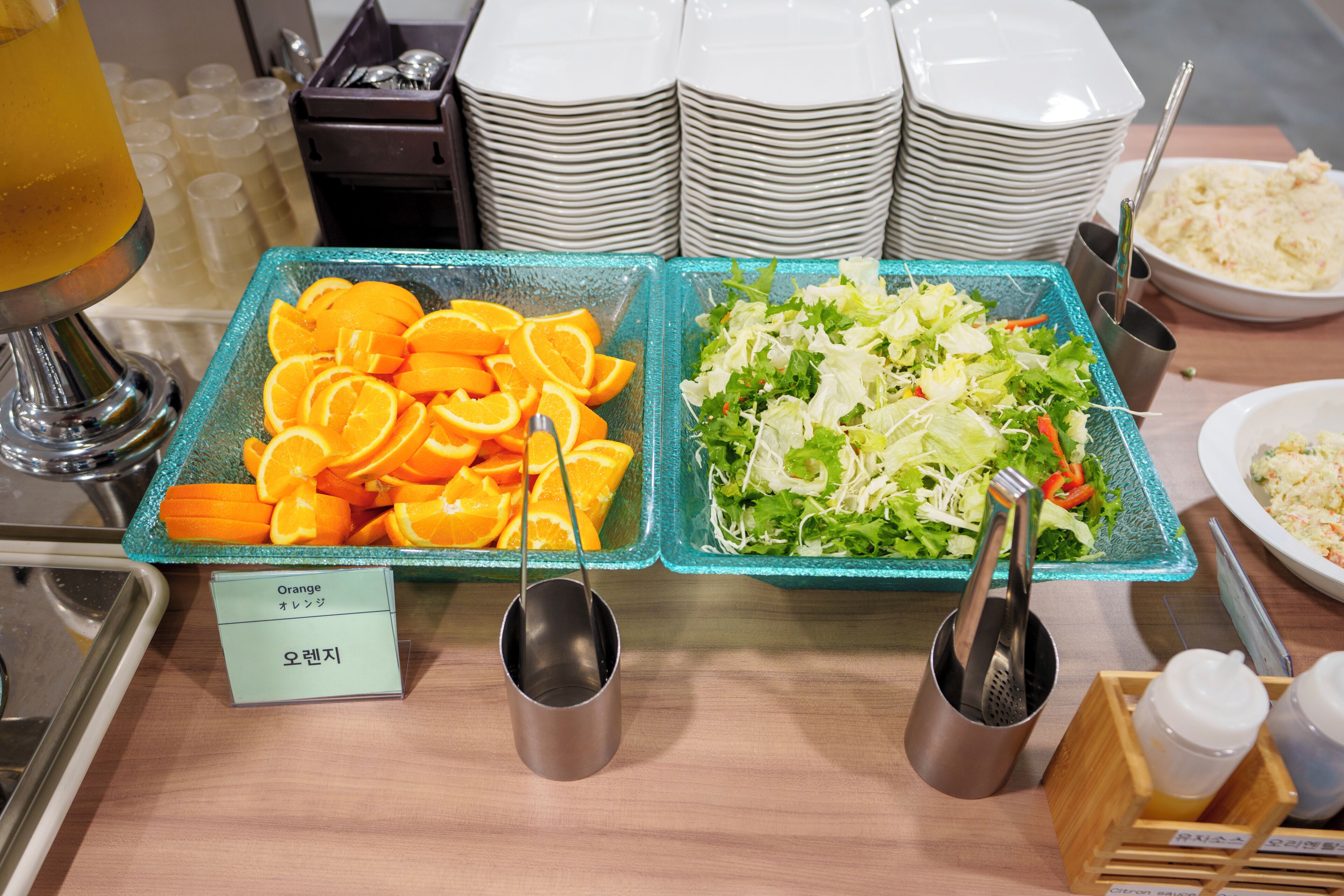 A buffet with orange slices and a salad.