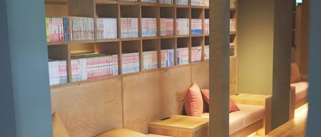 A reading area with bookshelves, cushioned seating, and a wooden floor.