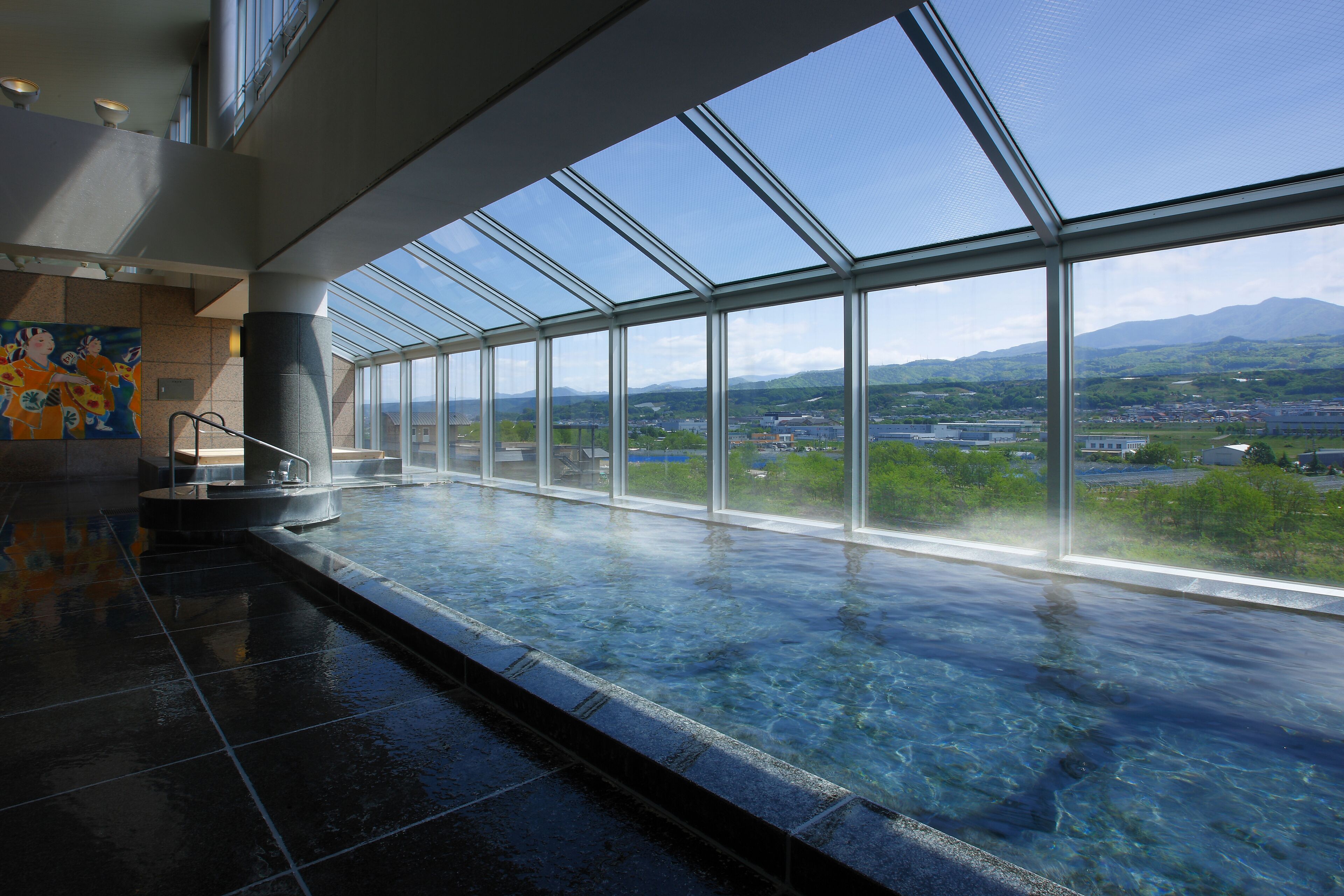 A spacious indoor area with a large glass window offering a view of a cityscape and mountains.