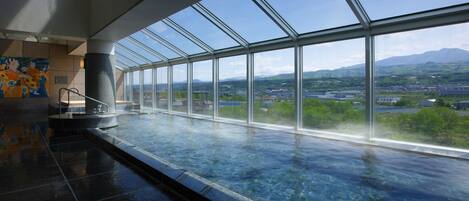 A spacious indoor area with a large glass window offering a view of a cityscape and mountains.
