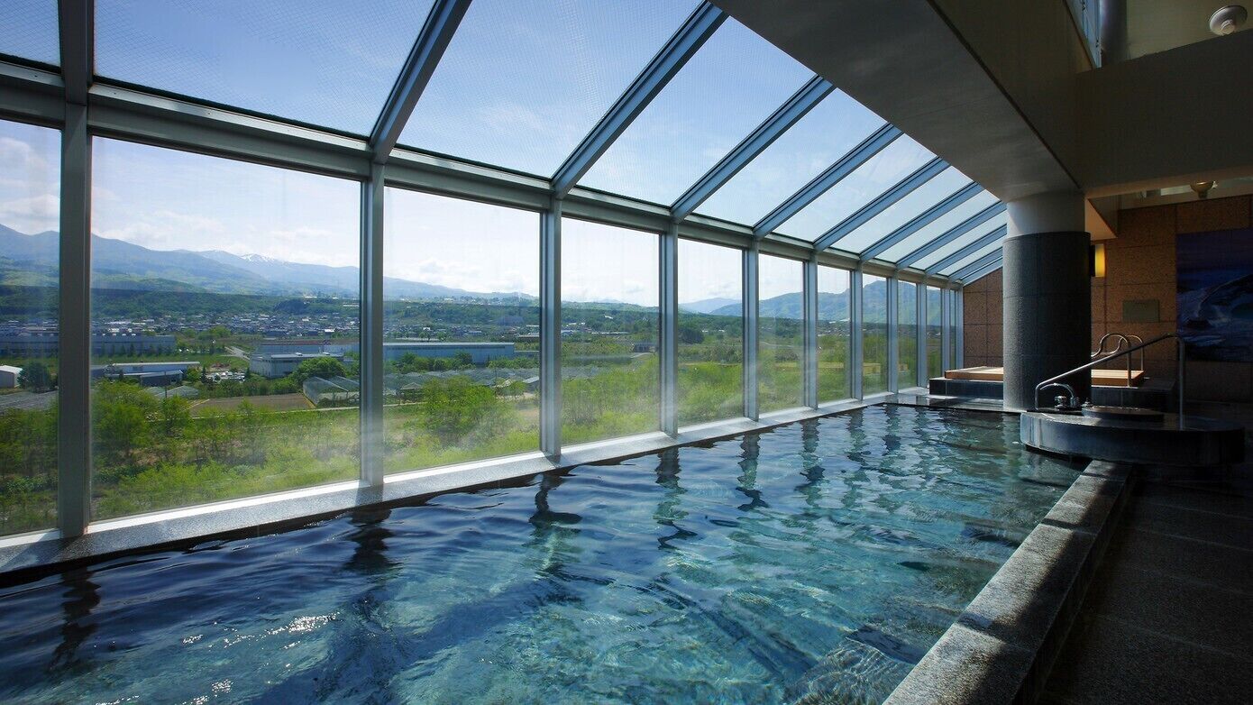 Una piscina interior transparente con amplias ventanas que ofrecen vistas a un paisaje montañoso.