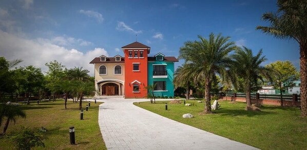 Un edificio grande y de varios colores, con una sección central roja, flanqueada por secciones azules y beiges.