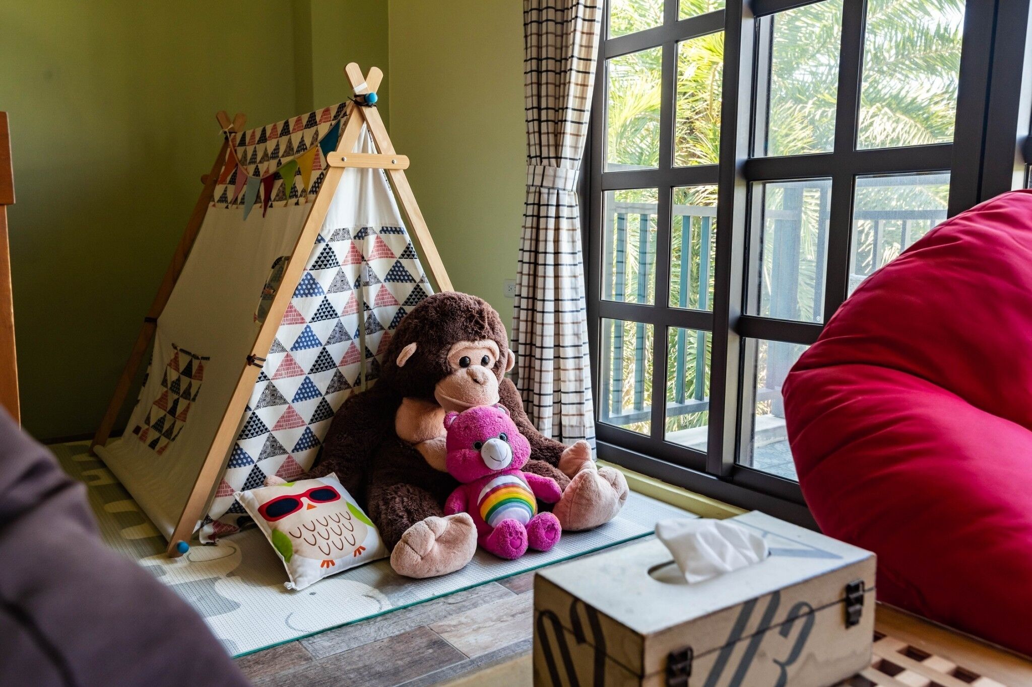 A cozy room with a window, a small tent, and a plush monkey toy.