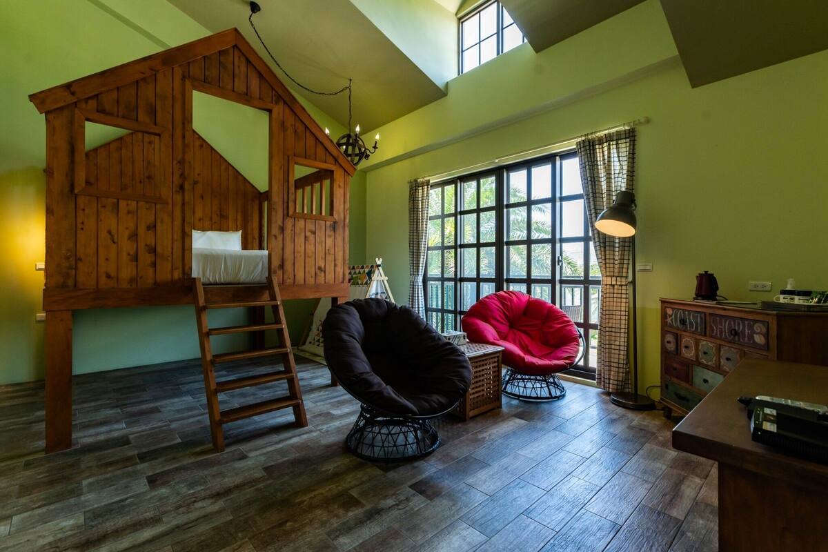 A loft-style bedroom with a wooden bunk bed, a ladder, and a red bean bag chair.