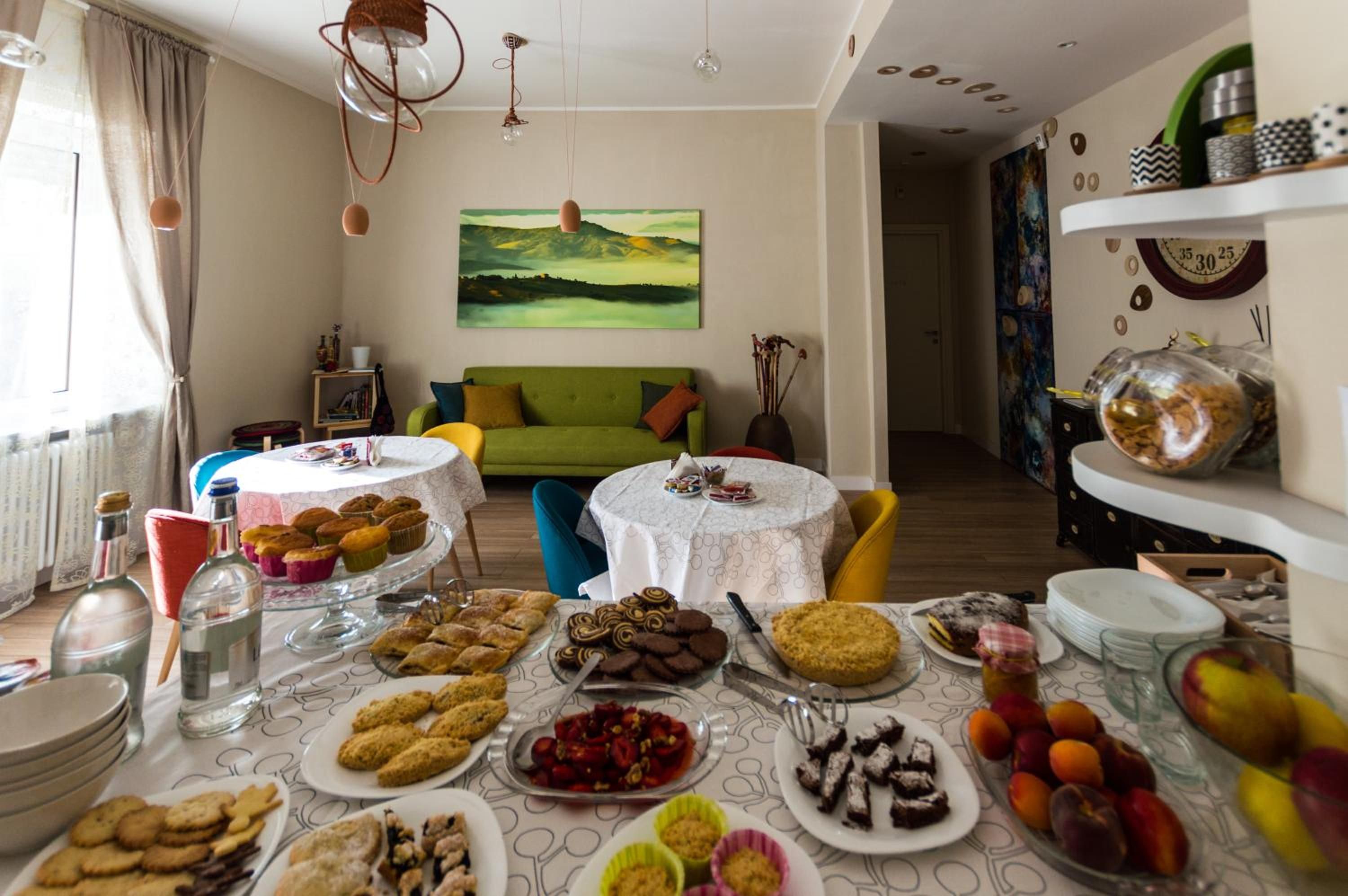 A dining area with a table set for a meal, a green sofa, and a painting on the wall.