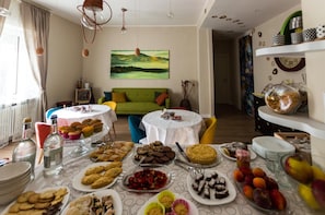A dining area with a table set for a meal, a green sofa, and a painting on the wall. - Leucos B&B (Potenza)