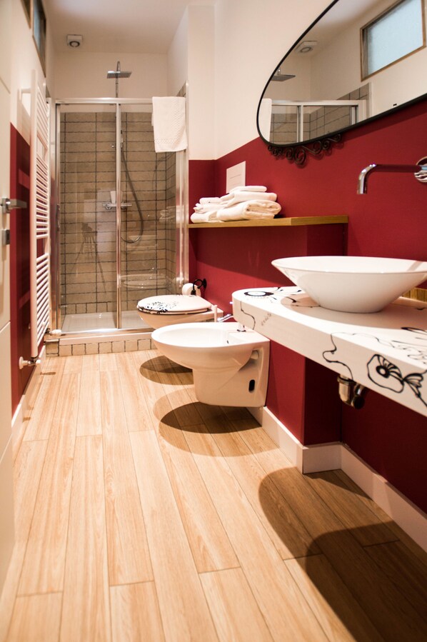Un baño moderno con ducha envuelta en vidrio, un lavabo blanco de gran tamaño y un inodoro.