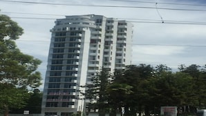 Ein hohes, modernes Apartmenthaus mit mehreren Balkonen und einer glatten Fassade.