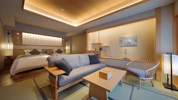 Moderni hotellihuone, jossa on sänky, sohva, tuoli ja pieni pöytä.