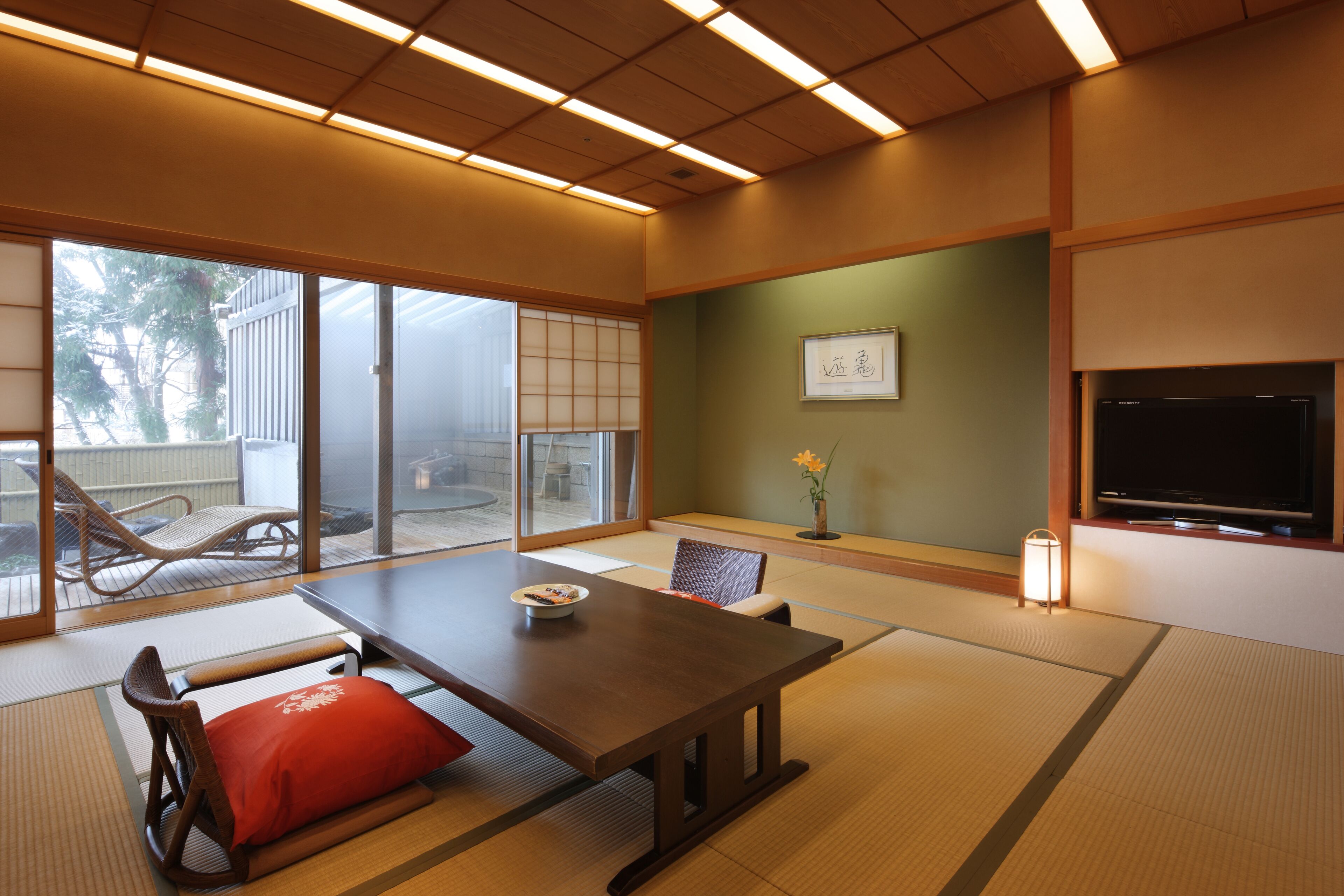 Una habitación tradicional japonesa con suelo de tatami, una mesa baja y un televisor.
