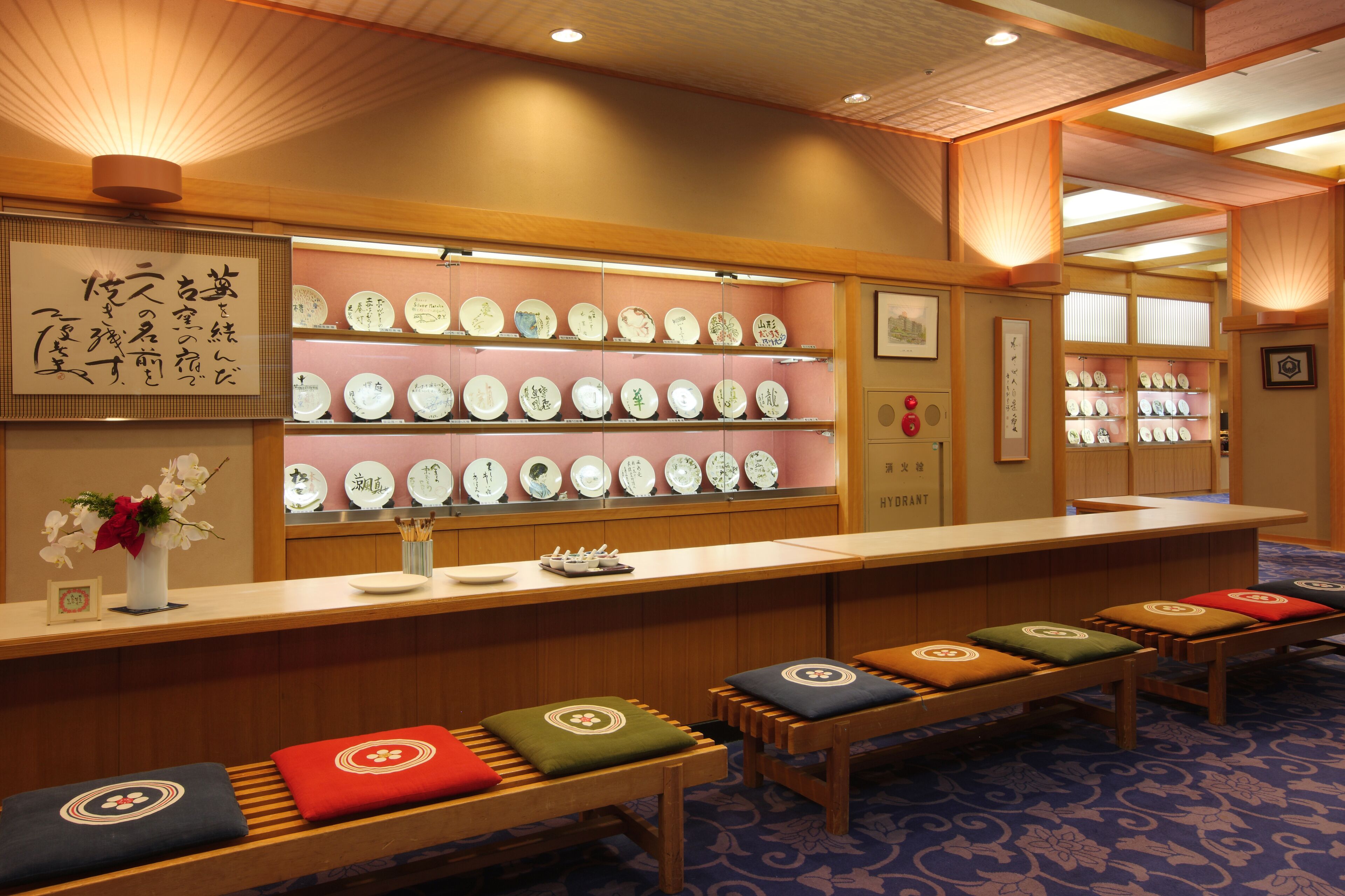 Una tradizionale stanza giapponese con tatami, una reception e una vetrina con piatti in ceramica.