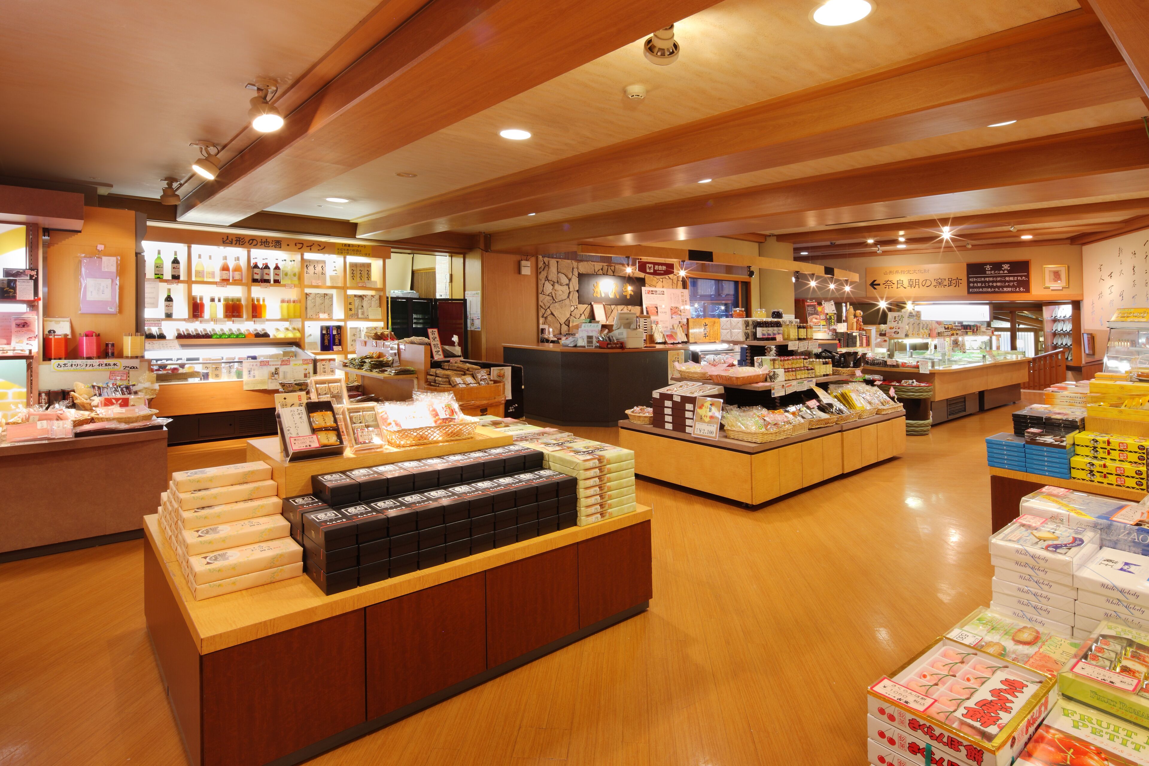 A well-lit store with wooden floors and shelves stocked with various products.
