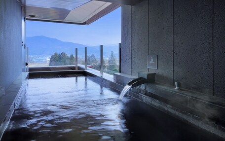 A modern indoor hot tub with a view of mountains and a cityscape.