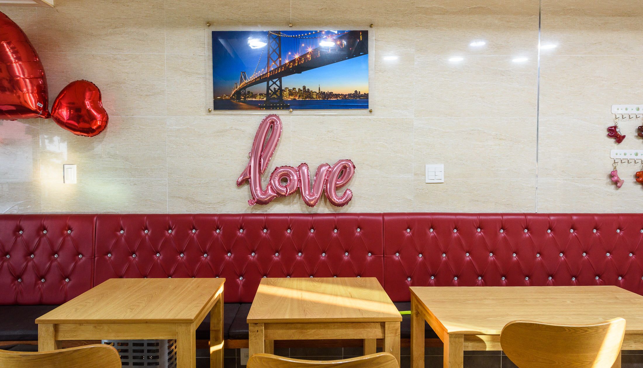 Interior de un restaurante con un banco acolchado rojo, mesas de madera y un letrero que dice 'amor'.