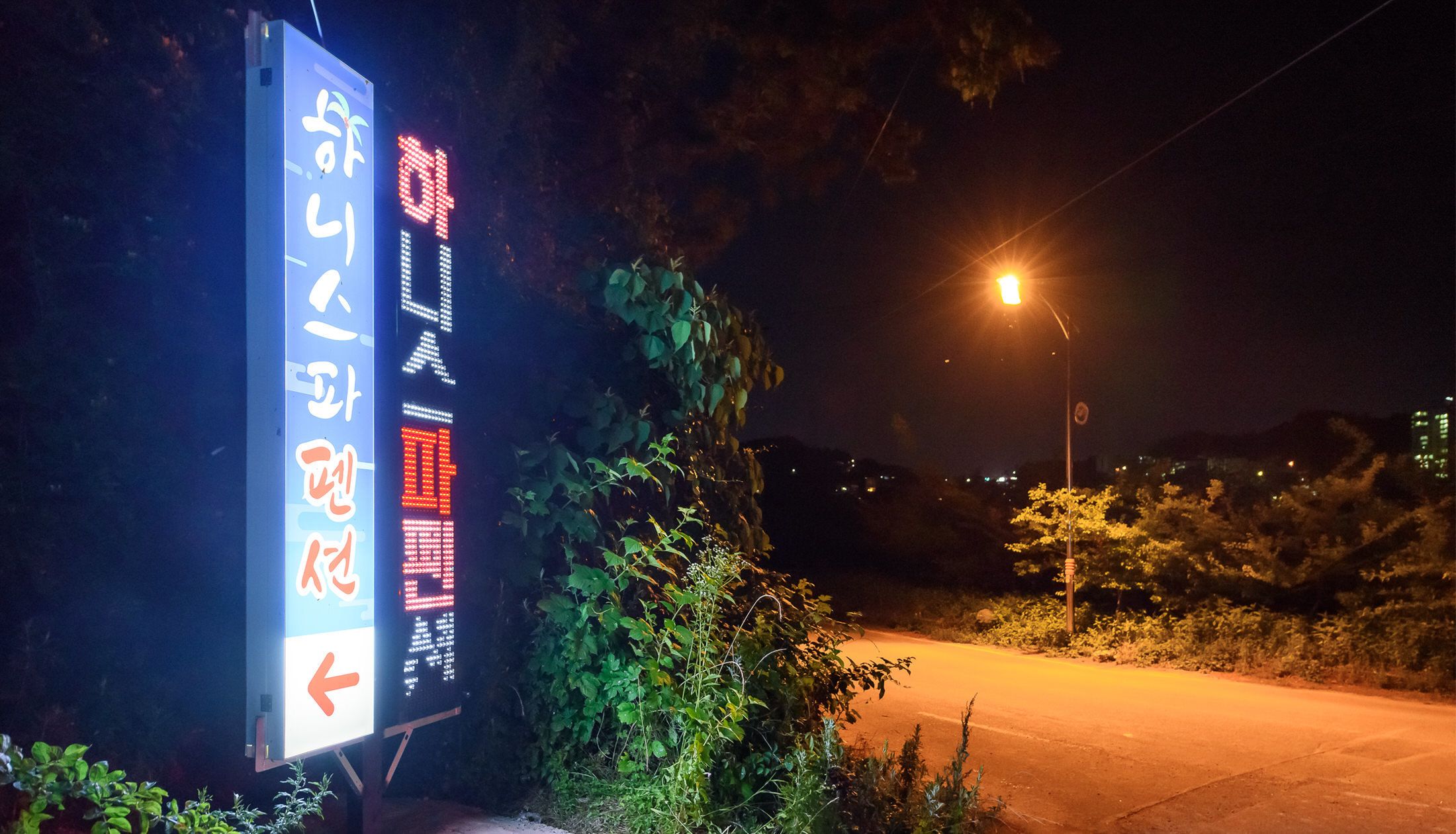 A nighttime street scene with a digital sign displaying information.