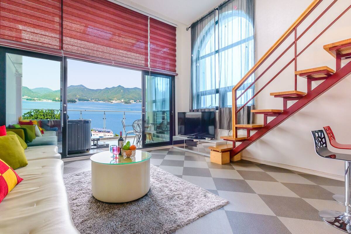 A modern living room with a sofa, a coffee table, and a staircase.