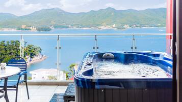 Un jacuzzi en un balcón con vista a una montaña y un cuerpo de agua.