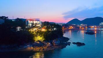 A coastal hotel with a view of the water and mountains in the background.