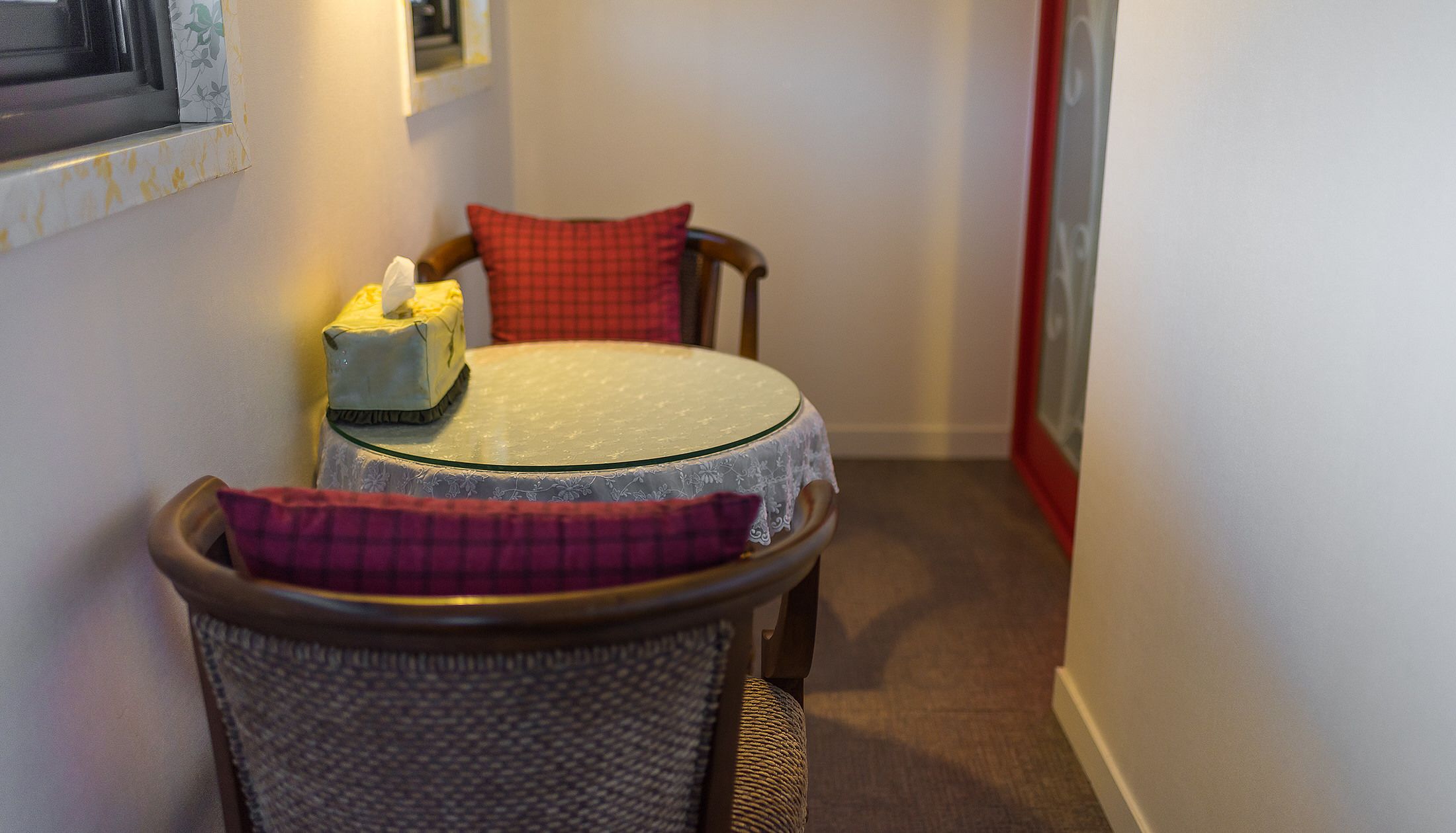 A small dining area with a round table, two chairs, and a tissue box on the table.