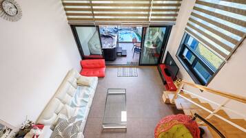 A modern living room with a sofa, a red chair, a glass coffee table, and a TV.