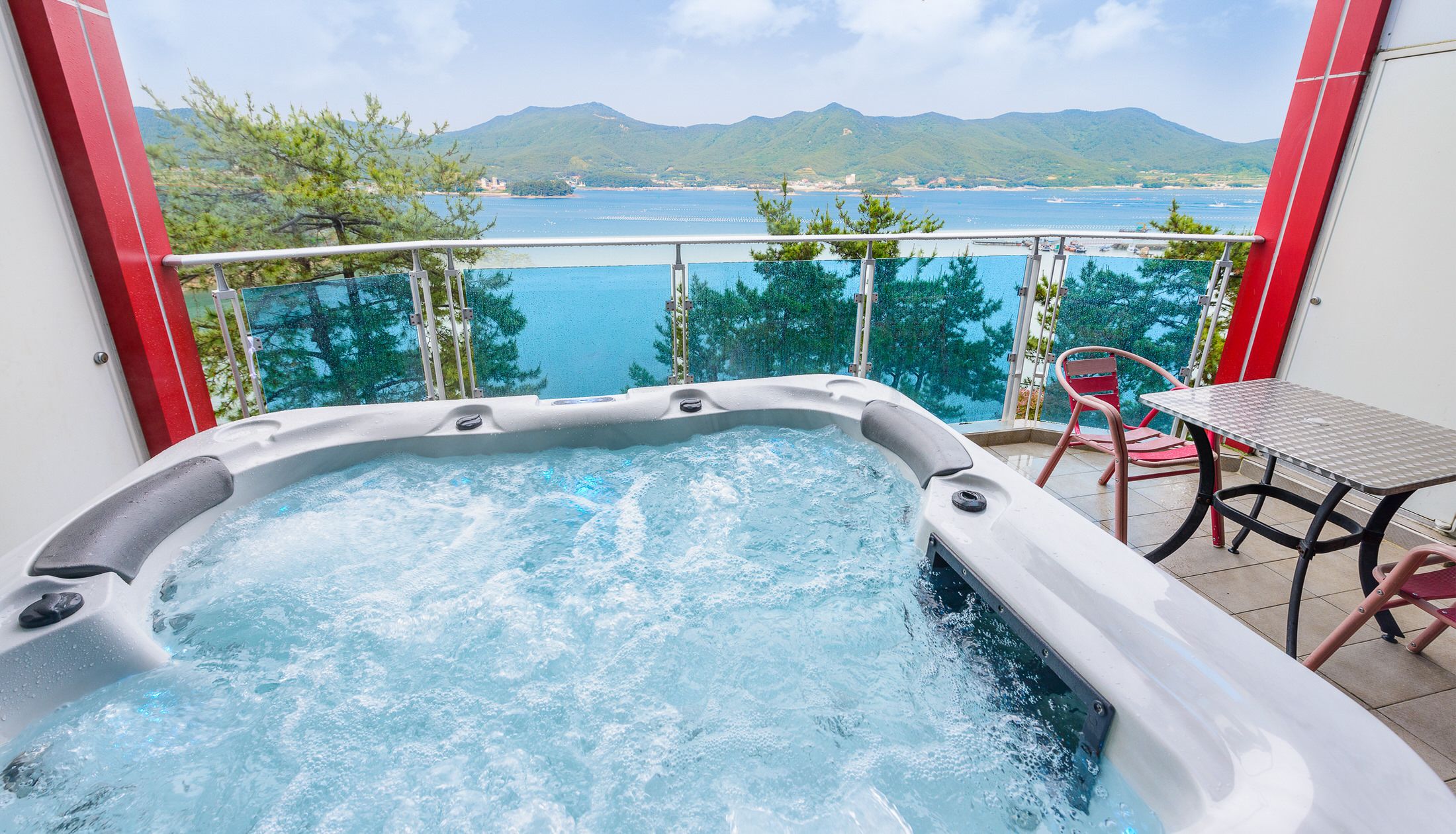 A hot tub with a view of a body of water and mountains.